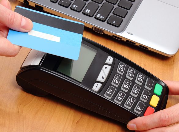 Paying with contactless credit card with NFC technology, credit card reader, payment terminal and laptop